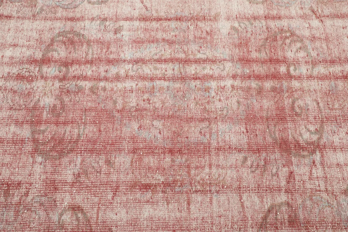 Detailed shot of the rug's central field, revealing the faded rose color and underlying geometric motifs.