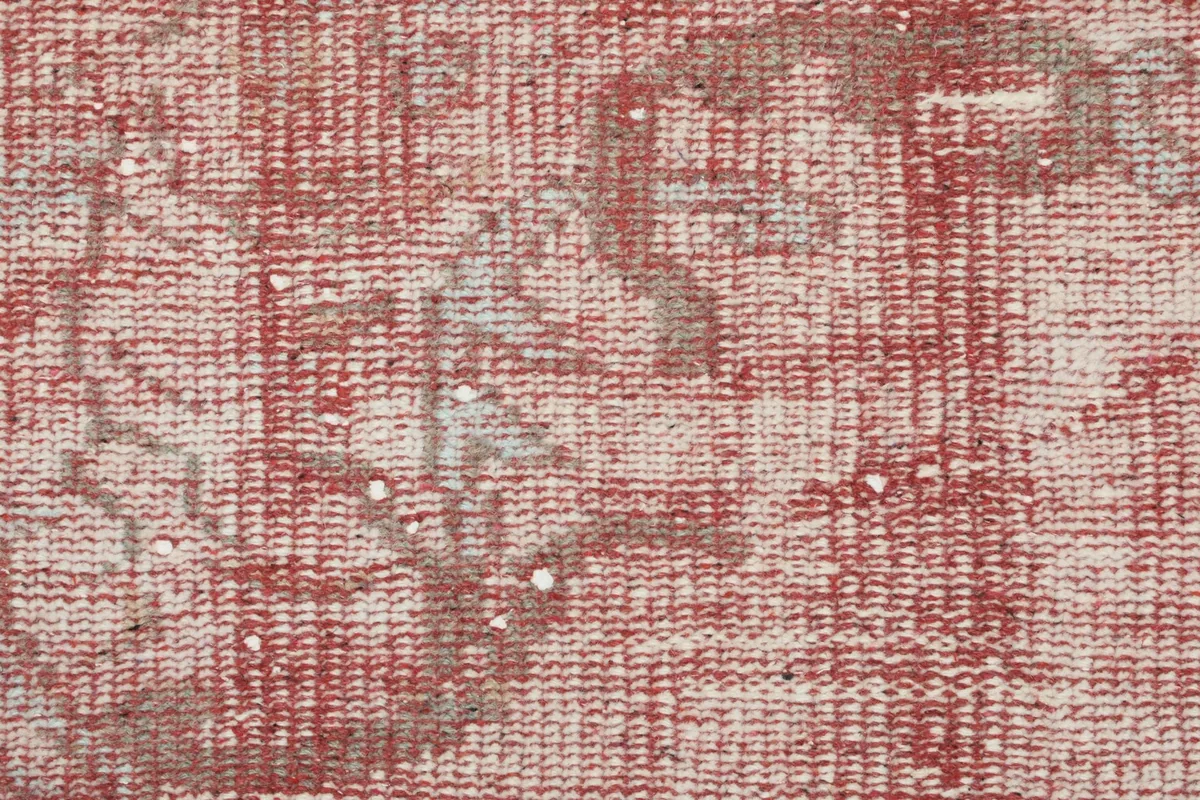 Macro view of the low wool pile, showing the hand-knotted texture and color blending of rose and gray.