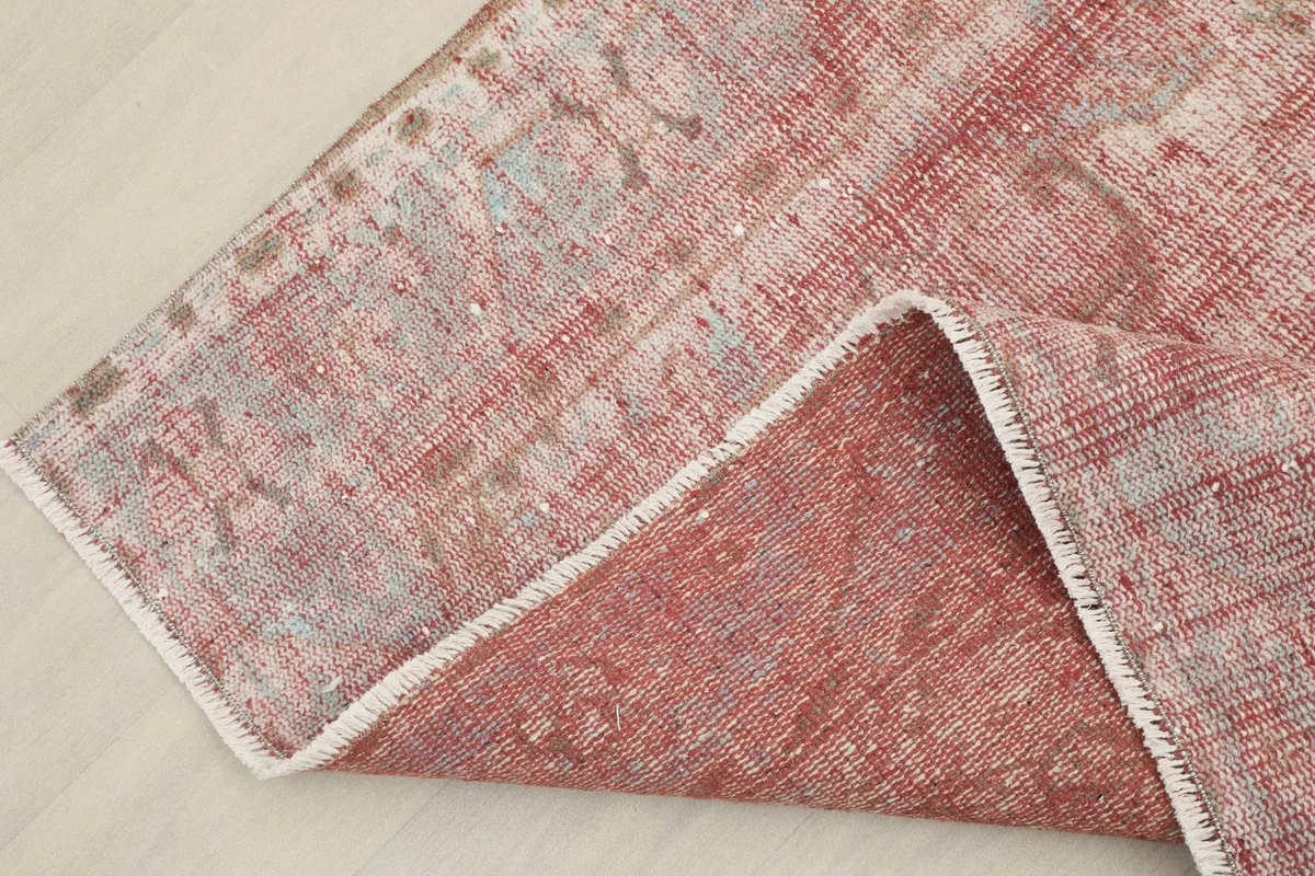 Folded corner showing the reverse side of the rug, revealing its cotton foundation and knotting.