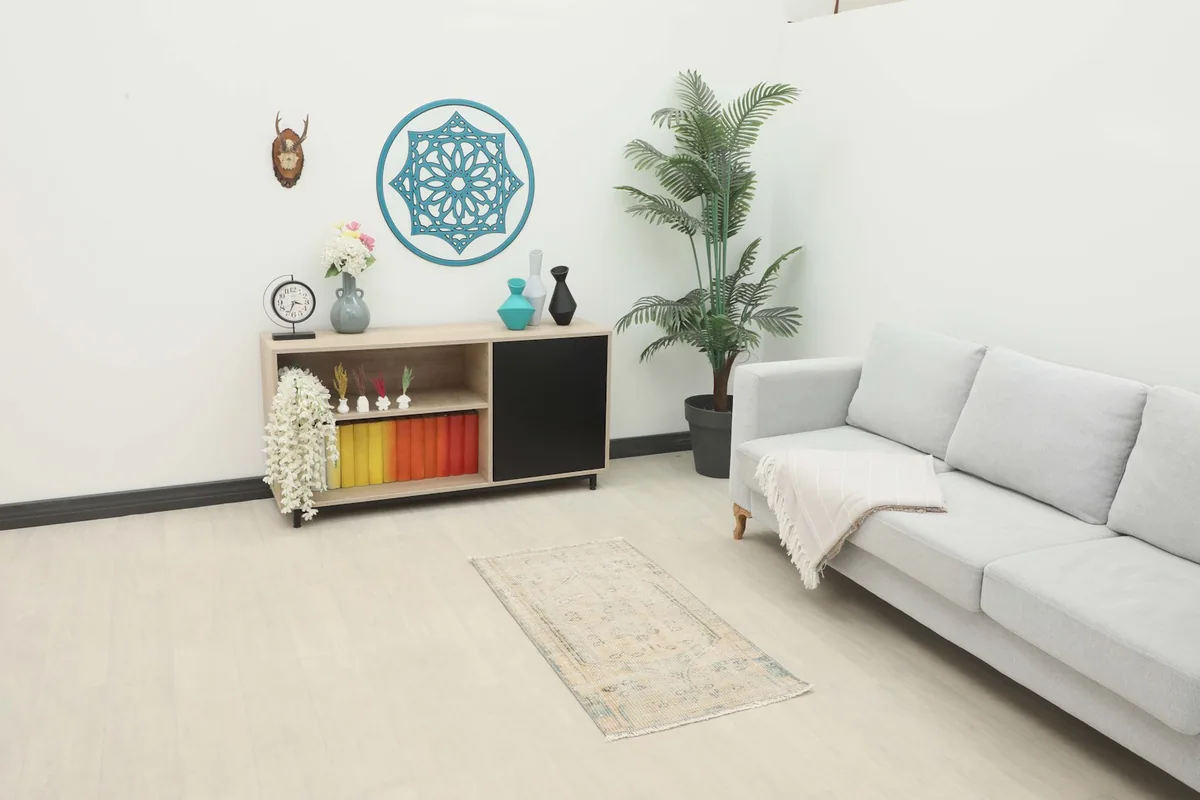 Ivory and blue vintage rug in a living room setting, placed on the floor in front of a sofa and cabinet