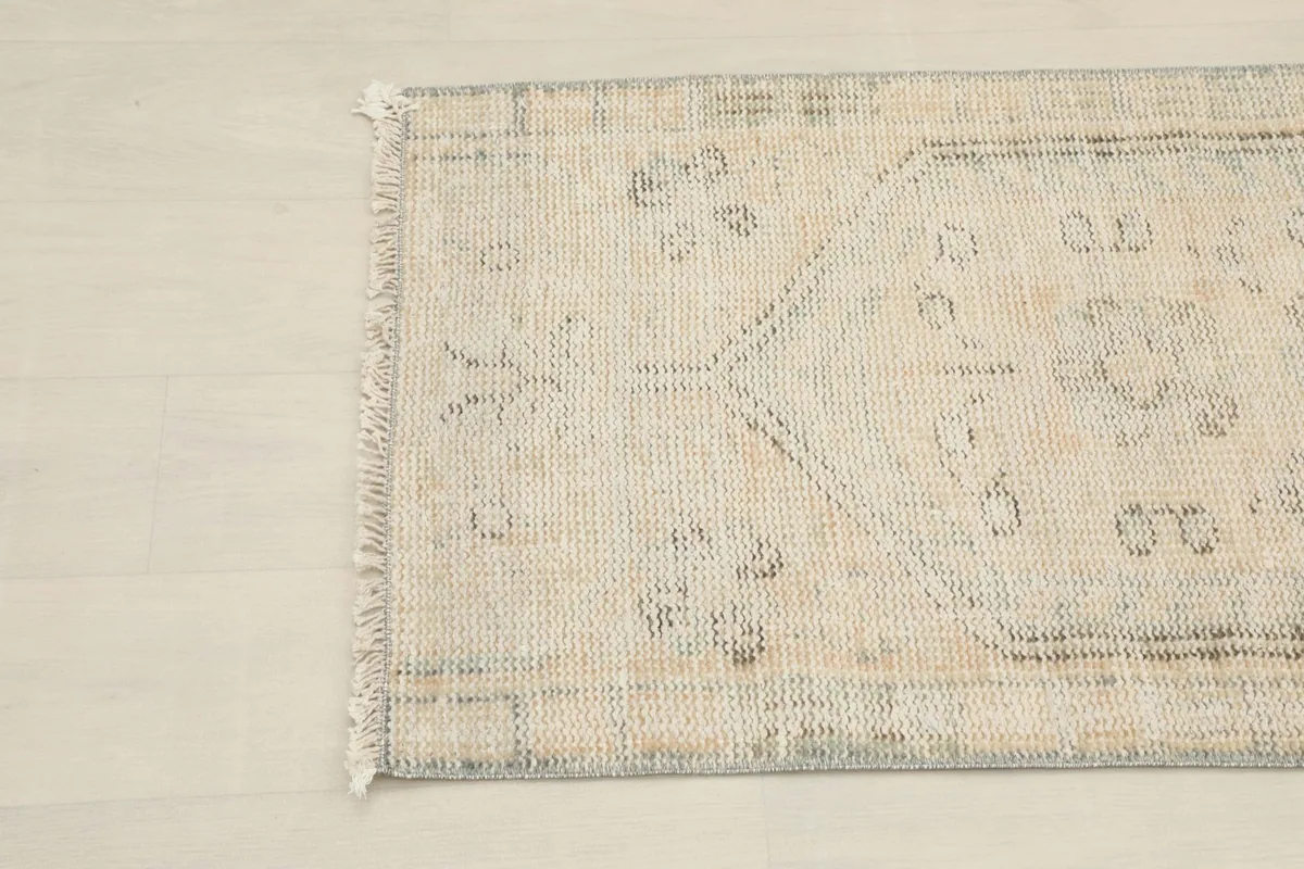 Close-up detail of the opposite end of the rug, showing the faded patterns and fringe