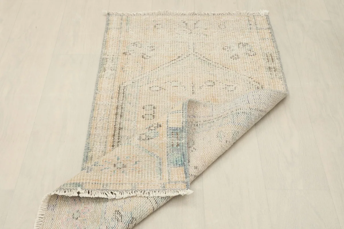 Angled view of the rug with one corner folded, revealing the underside and fringe
