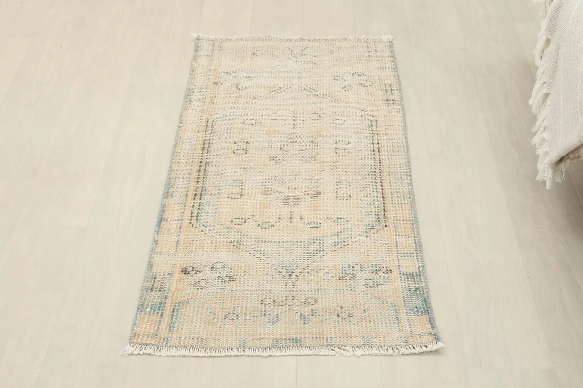 Overhead view of the ivory and blue vintage rug, showcasing its full pattern and shape on a light floor