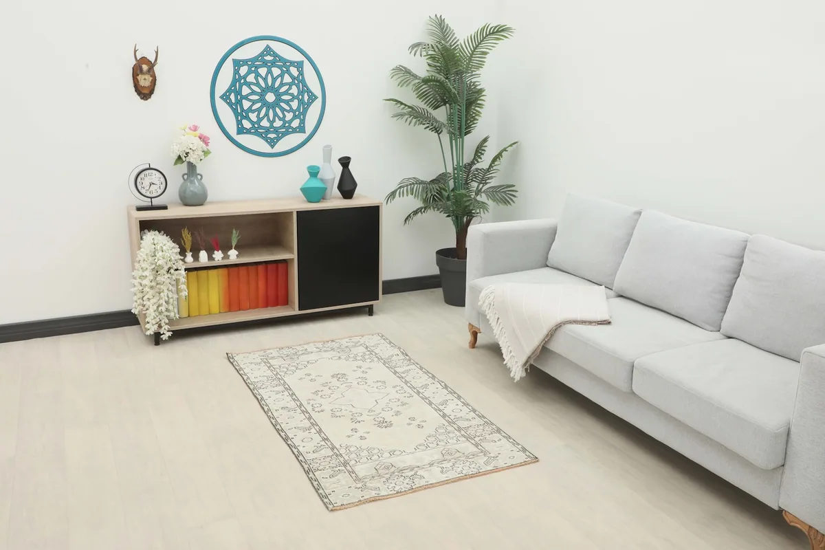 Ivory and gray vintage rug in a living room setting with a sofa and cabinet