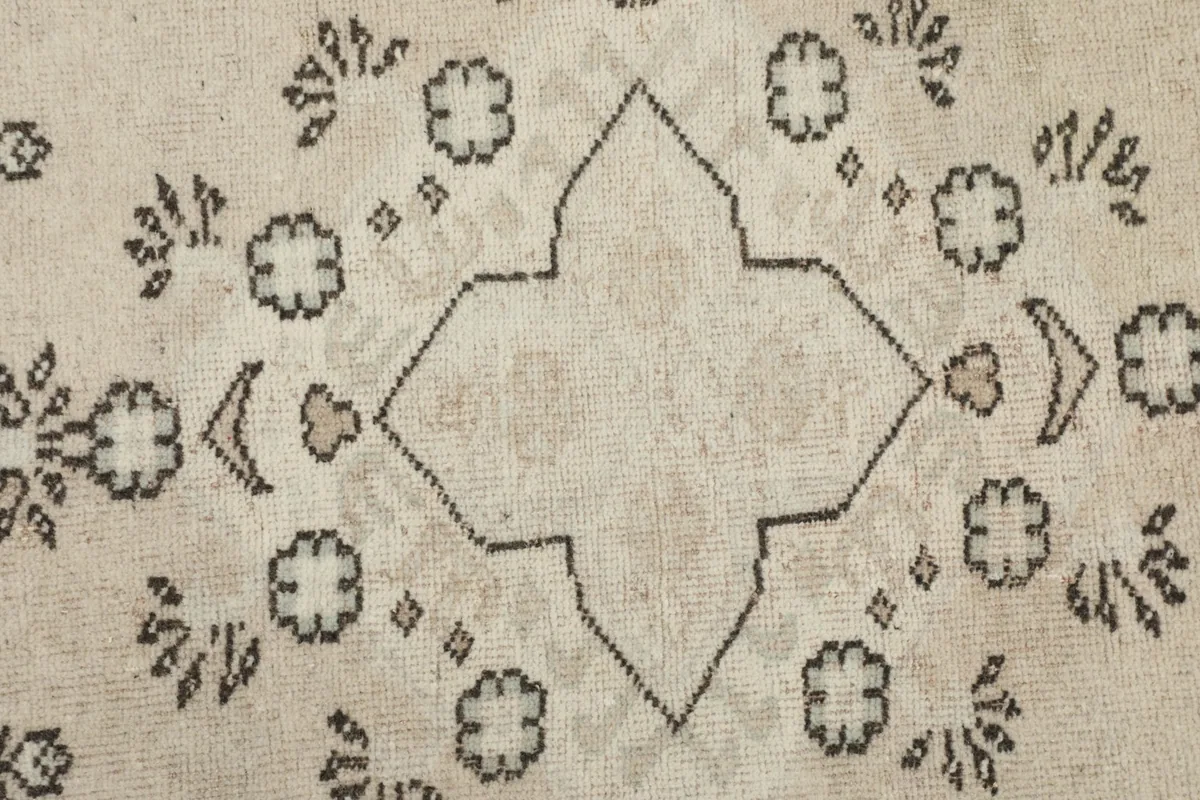 Close-up of the central motif and subtle color changes in the ivory field