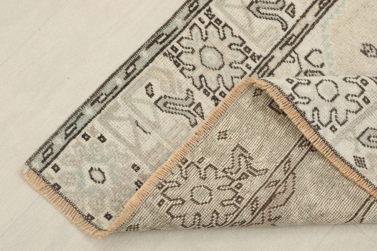 Corner of the rug folded back, revealing the backing and weave structure