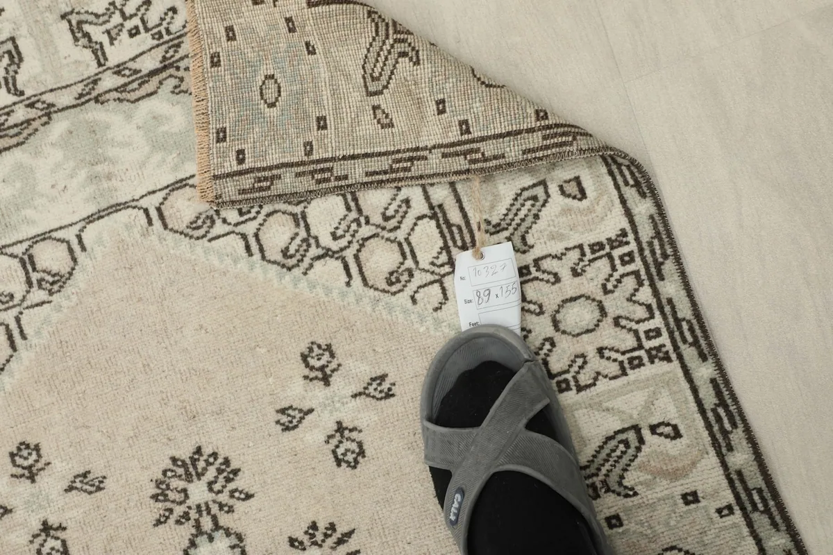 Foot in a slipper placed on the rug, indicating scale and low pile