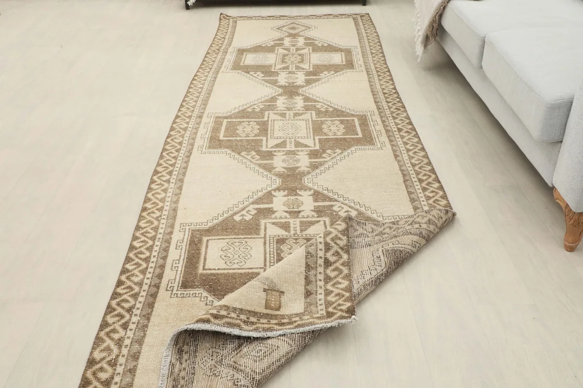 Runner rug partially folded, showcasing its reverse side and the full length in a room.