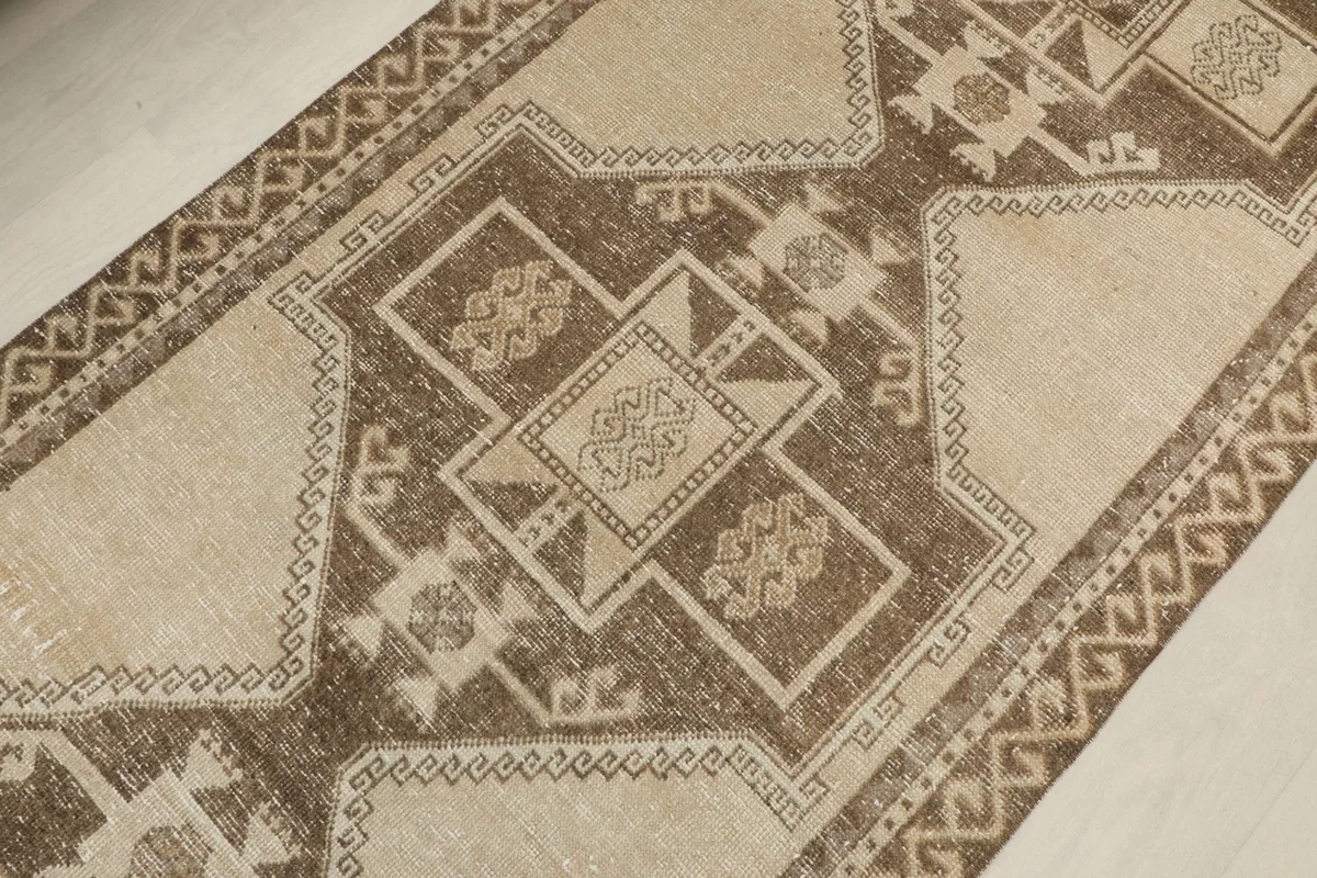 Detailed view of the central geometric motifs in brown and beige tones, showing the wool pile.