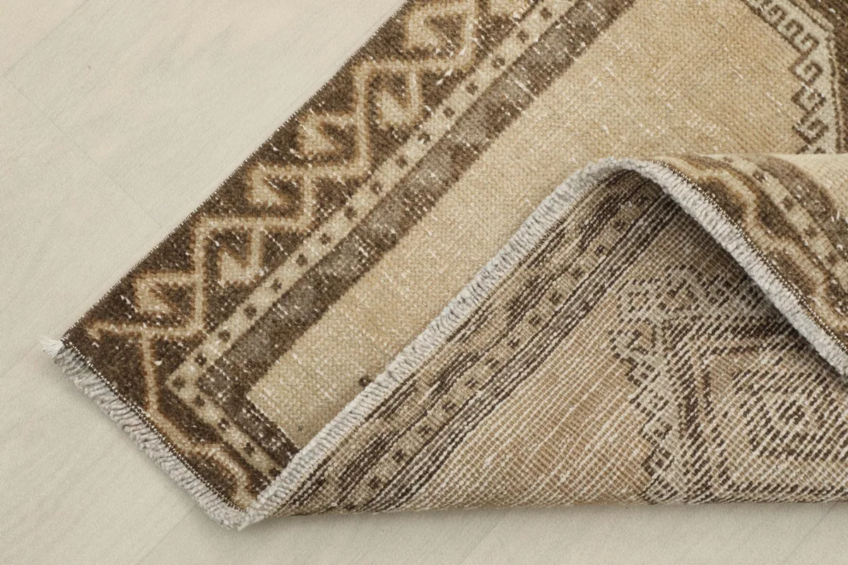 Corner of the runner rug folded to show the thickness of the wool pile and cotton foundation.