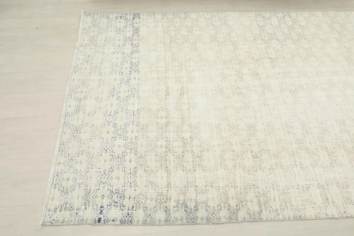 Close-up of the rug's border, showing the faded blue geometric motifs
