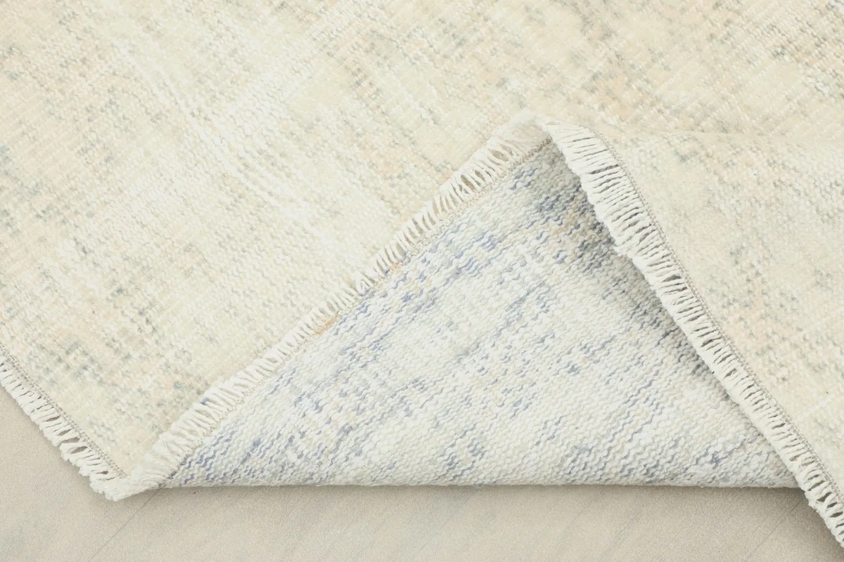 Corner of the rug folded back, showing the cotton foundation and hand-knotting on the reverse