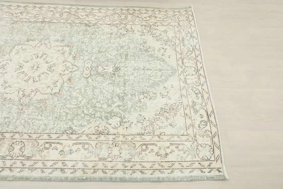 Close-up angled view of the rug's corner, highlighting the detailed cream and tan border.