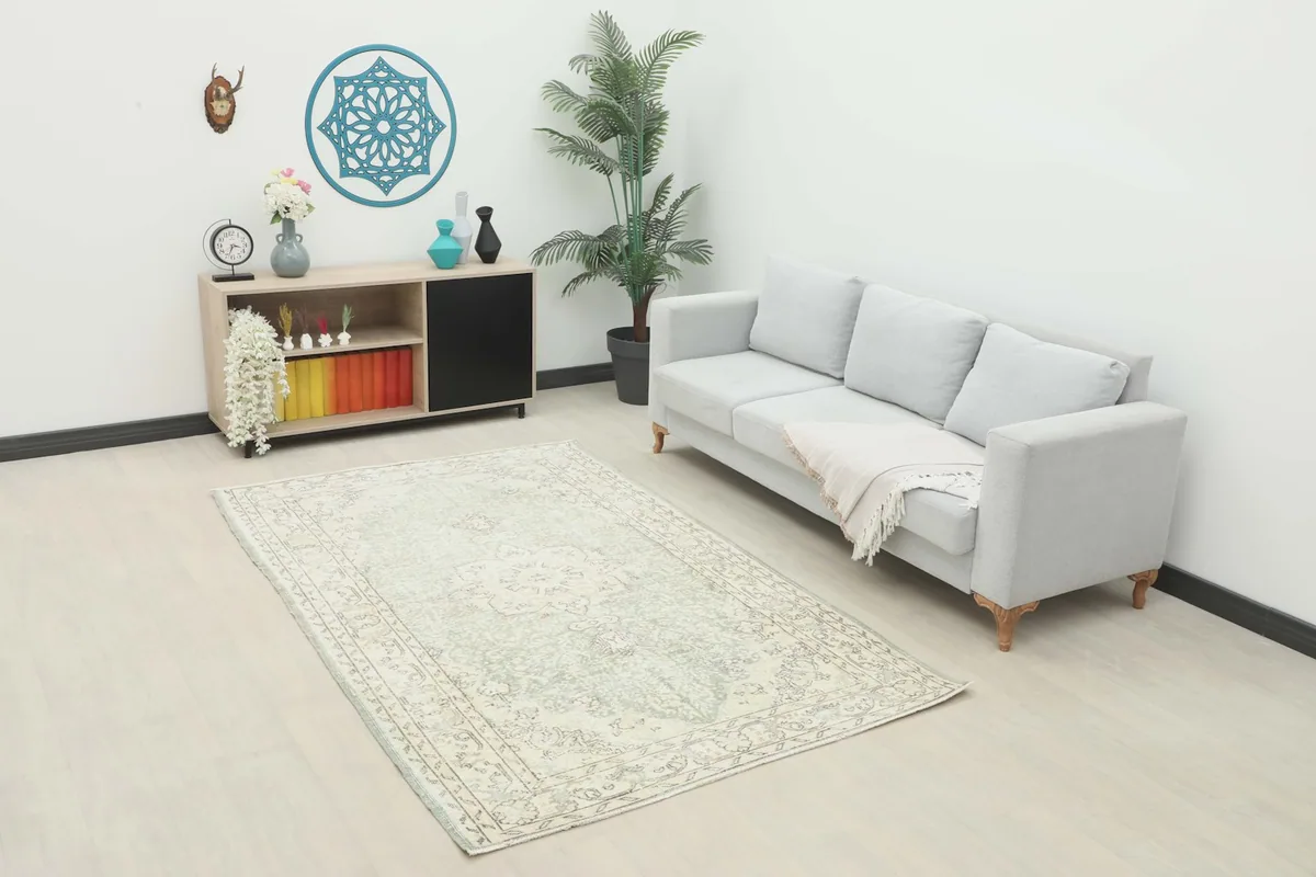 Vintage green and cream Anatolian rug placed in a modern living room setting with a light sofa.