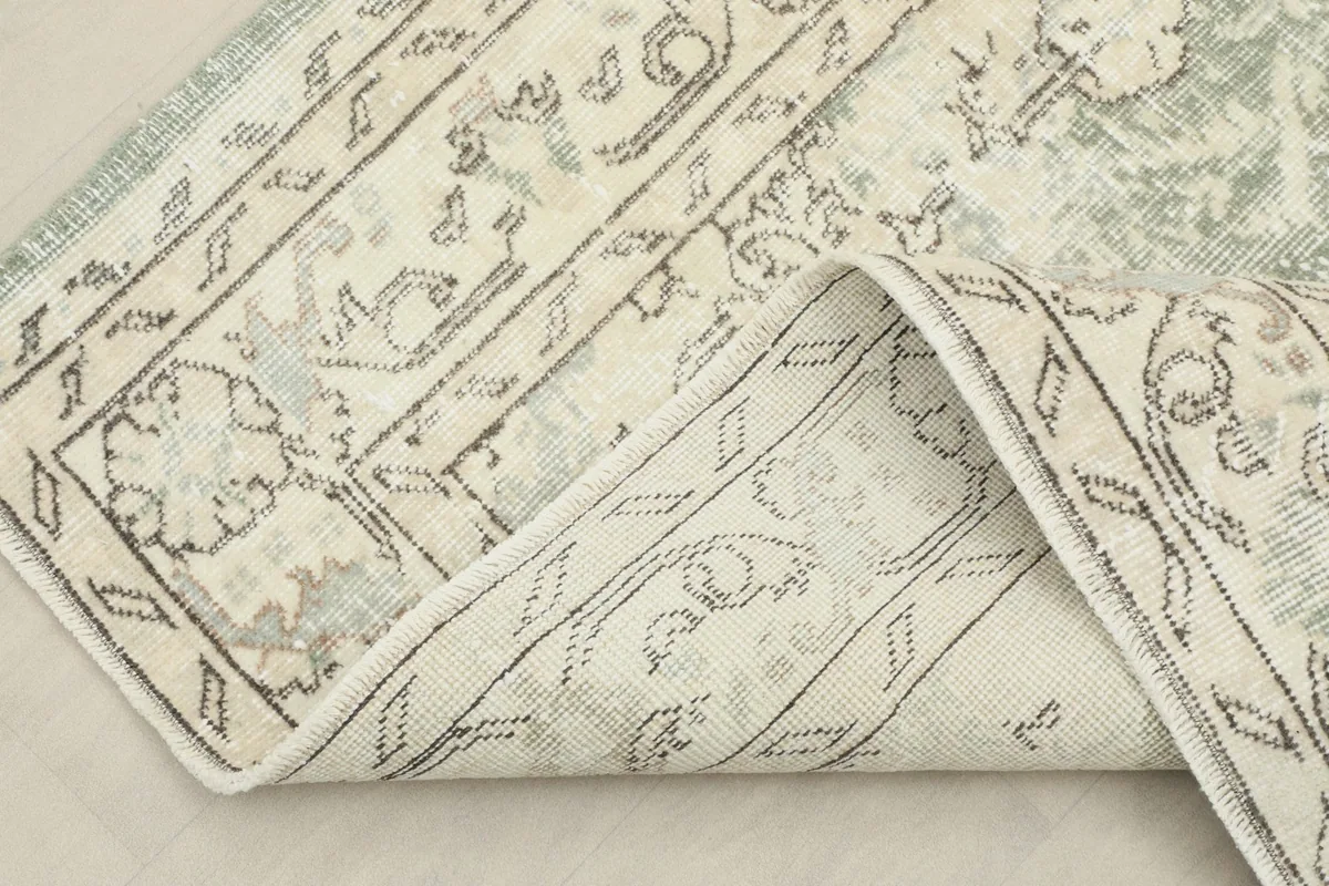 View of the rug folded back, showing the back of the hand-knotted cotton foundation and wool pile.