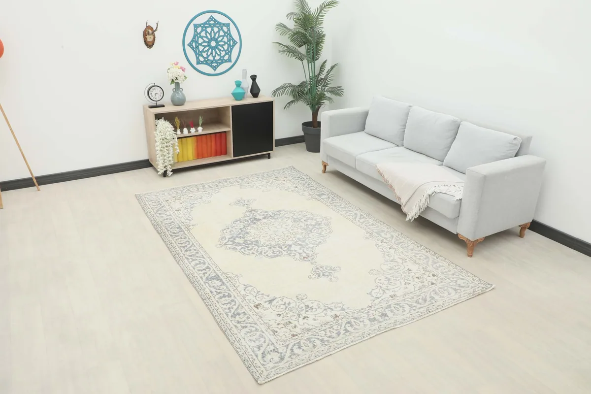 Ivory and gray vintage rug placed in a modern living room setting with a light gray sofa.