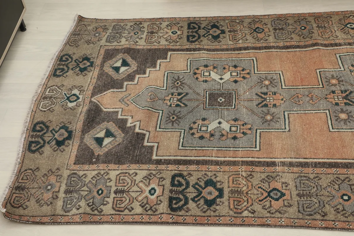 Angled view highlighting the intricate geometric and tribal motifs in the gray, orange, and black sections of the rug.