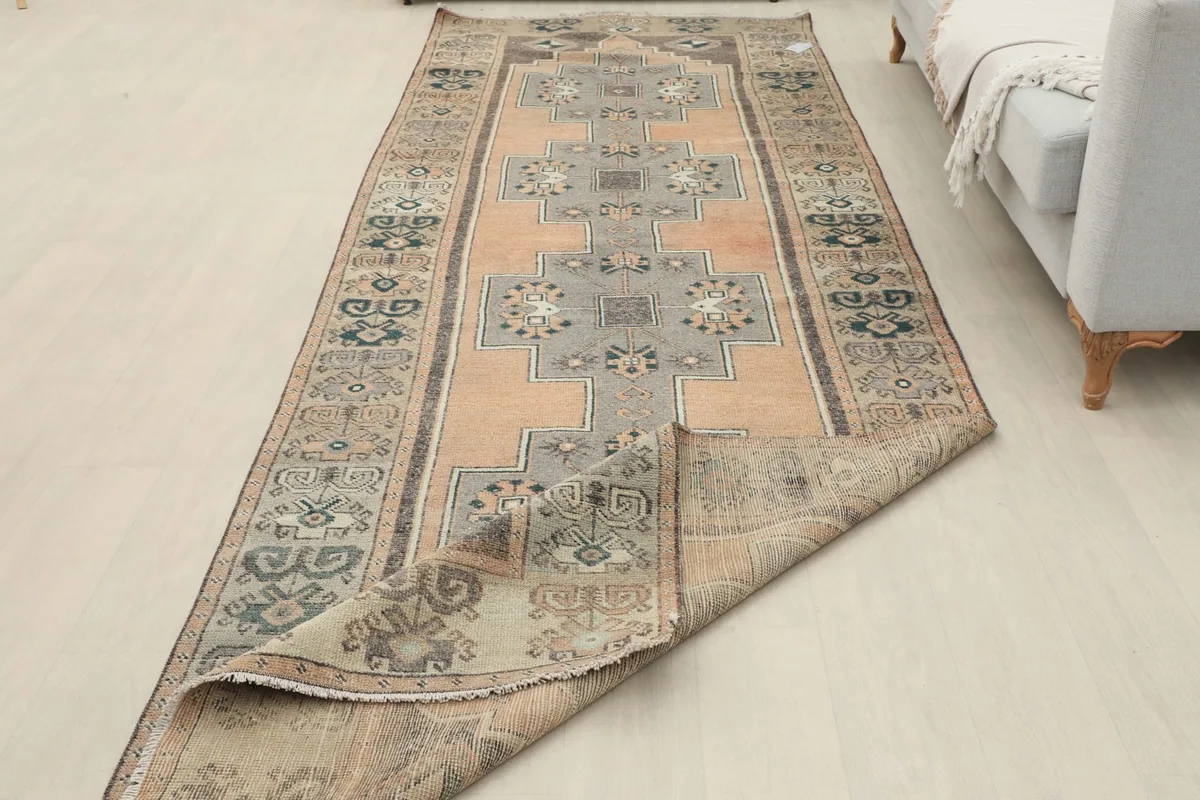 View of the runner rug in a room, partially folded to show the back, emphasizing its length and texture.