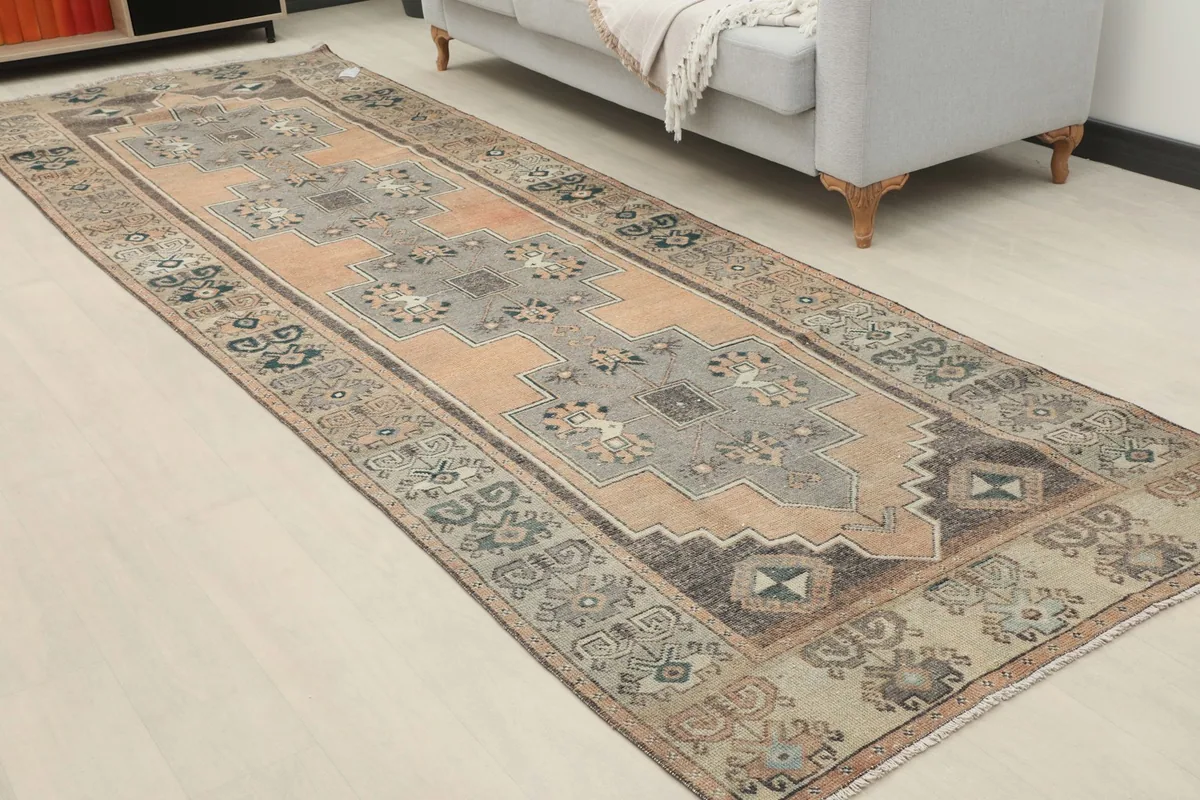 Full length view of the runner rug in a room, showcasing its vibrant orange, gray, and black colors and geometric design.