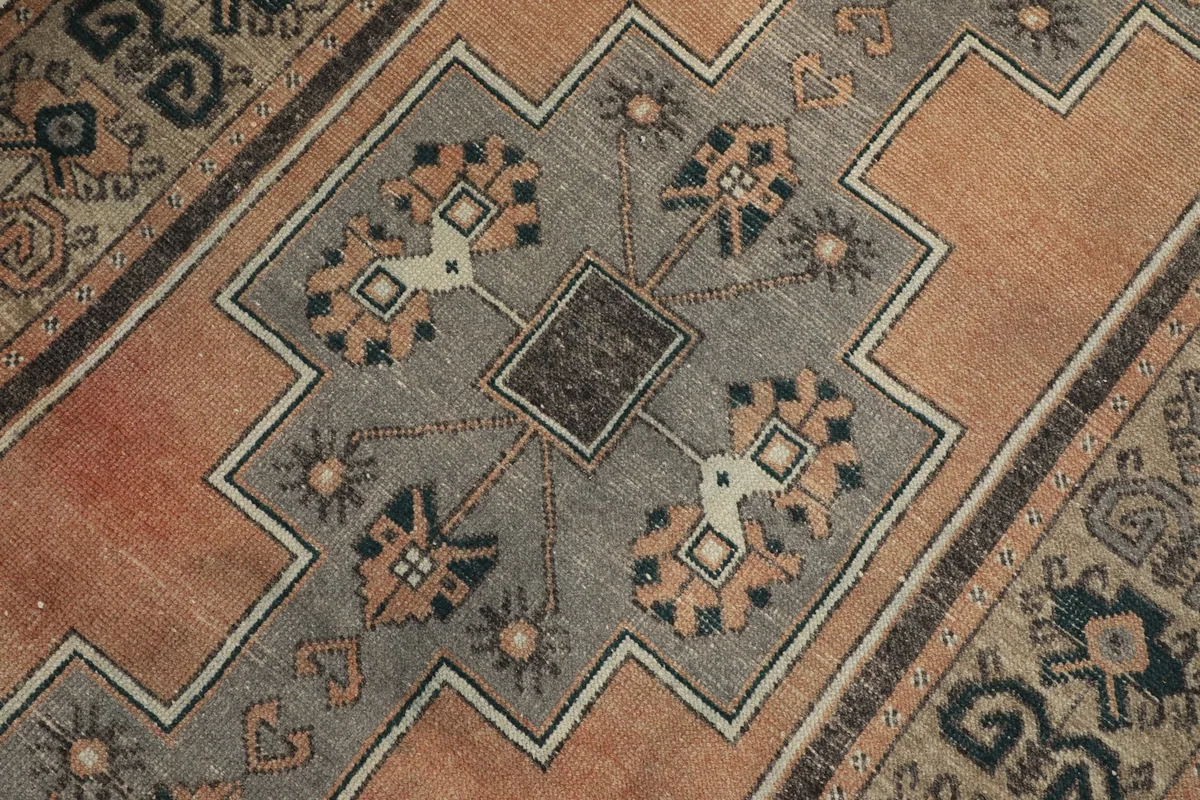 Detailed close-up of the central gray geometric medallion-like pattern with blue and beige accents on the orange field.