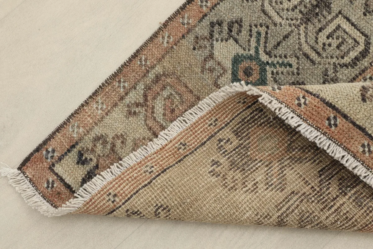 Corner of the rug folded back to reveal the hand-knotted wool pile on a cotton foundation and the fringe.