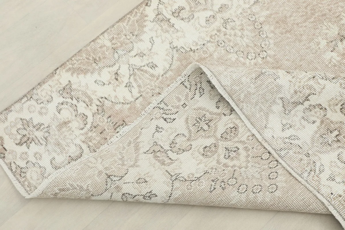 Corner of the rug folded back to reveal the cotton foundation and the reverse side of the hand-knotting