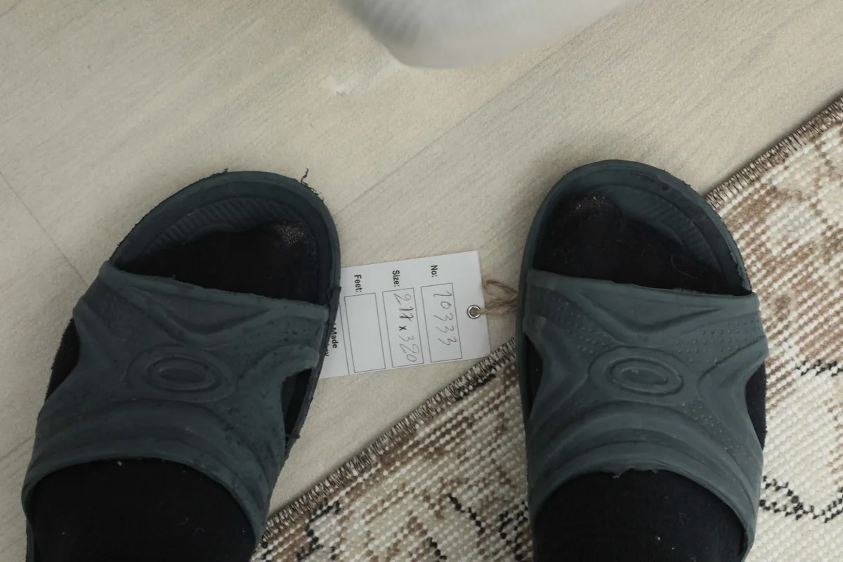 Overhead view showing the tag attached to the rug, next to a pair of feet for scale reference
