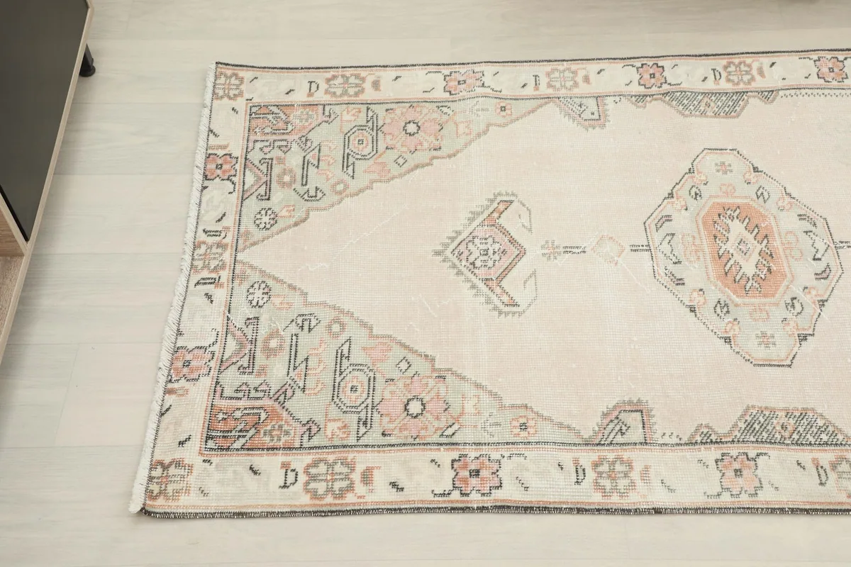 Close-up angled view of the rug's pattern and border, highlighting the vintage patina
