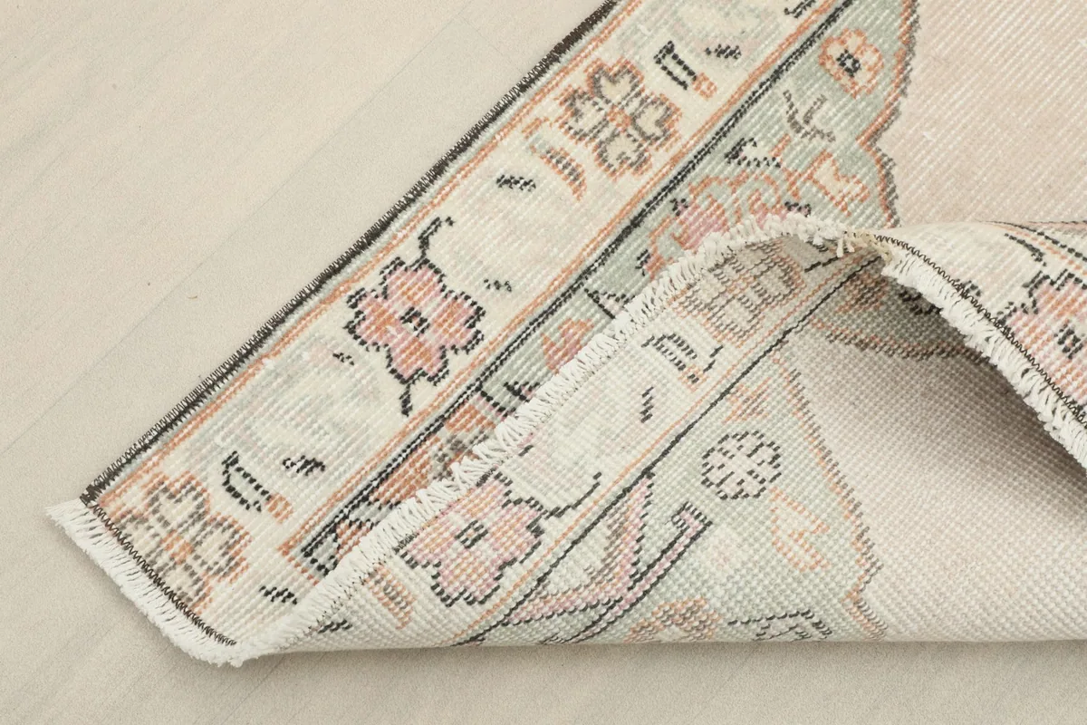 Corner of the rug folded back, revealing the cotton foundation and fine knotting