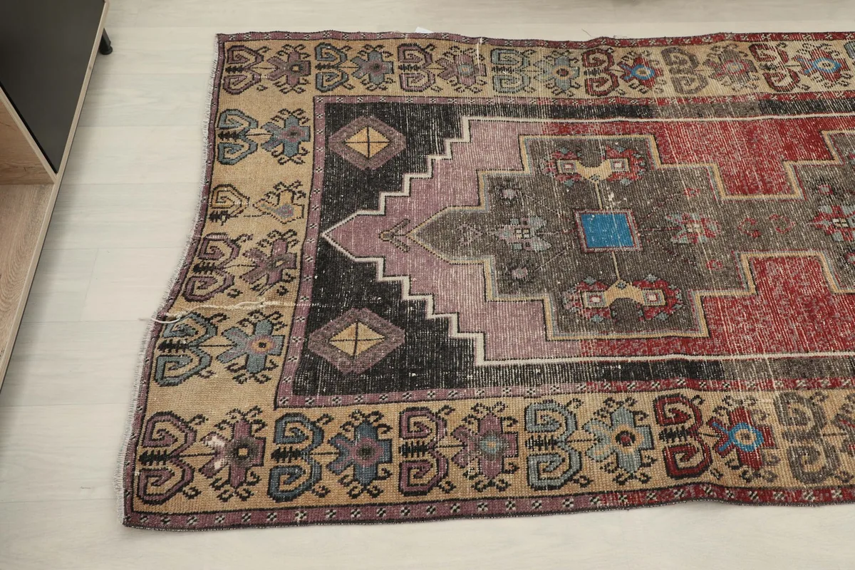 Close-up angled view of the rug's end, revealing the intricate tribal motifs in the beige border