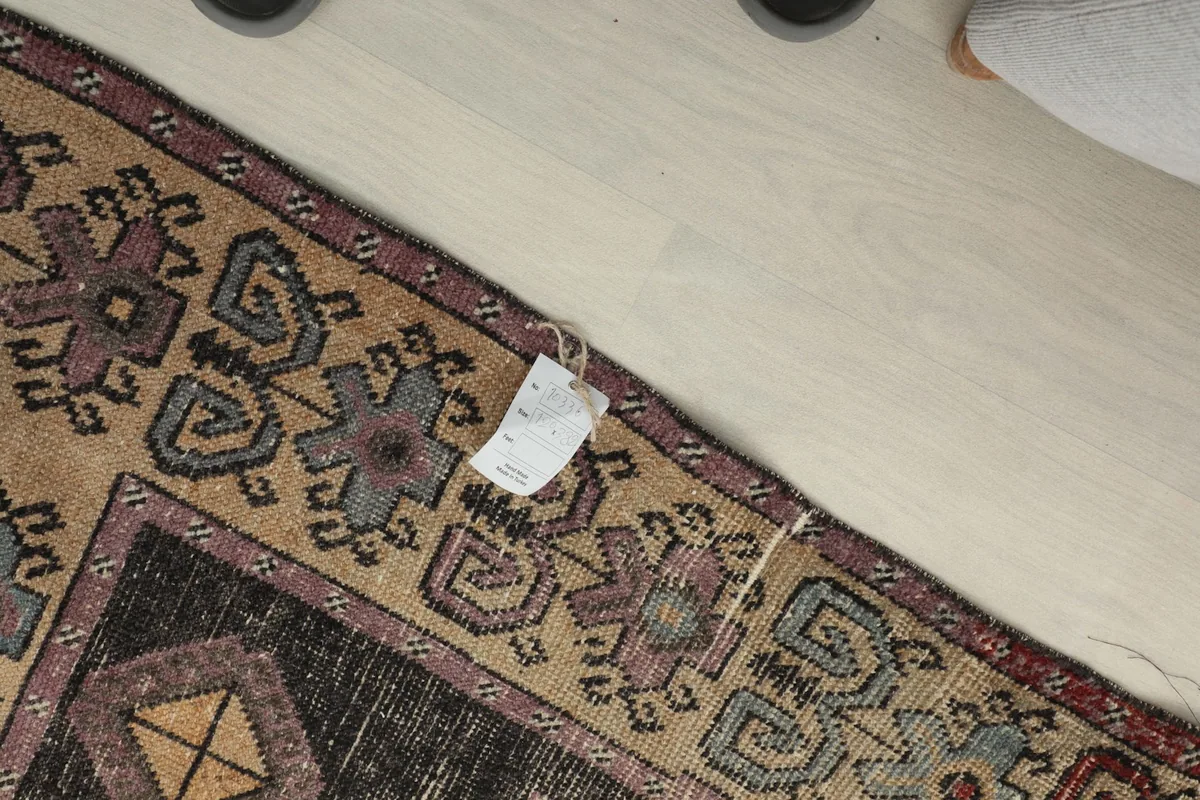 Close-up of the rug's corner with a tag, showing the beige border and purple details