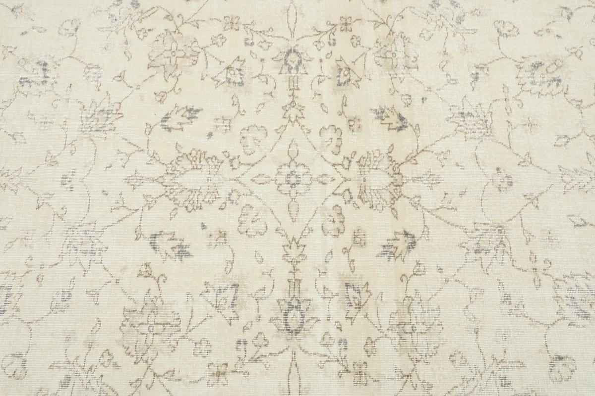Close-up of the central floral medallion and surrounding motifs in the ivory rug