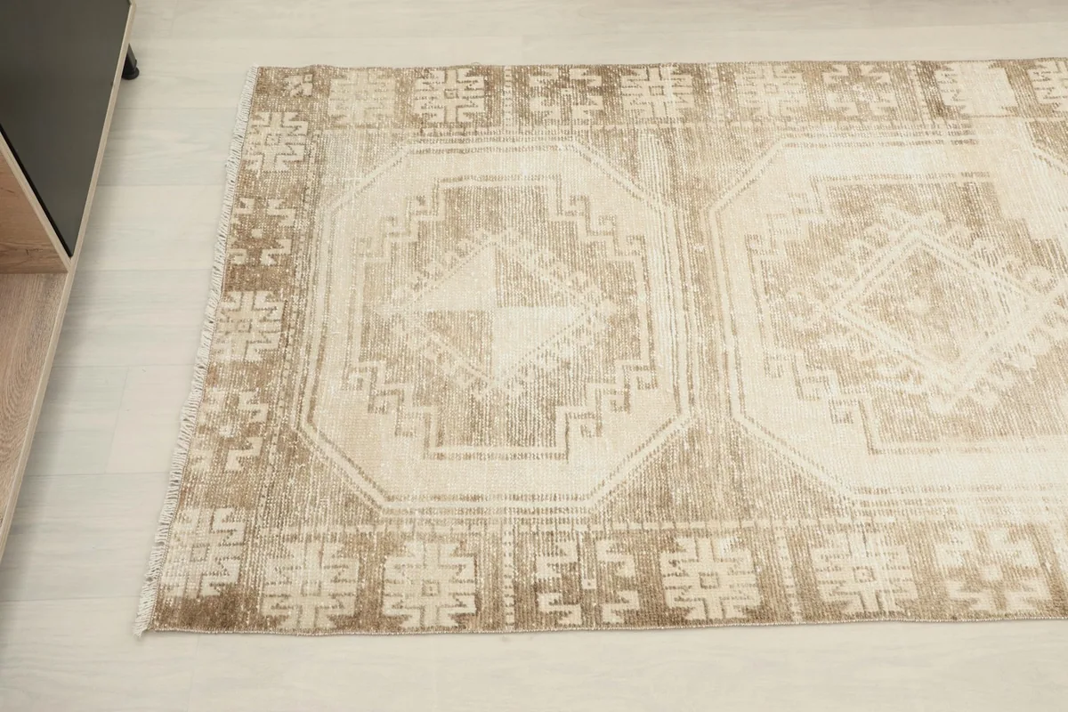 Detail view of the center medallion and surrounding tribal motifs on the beige rug