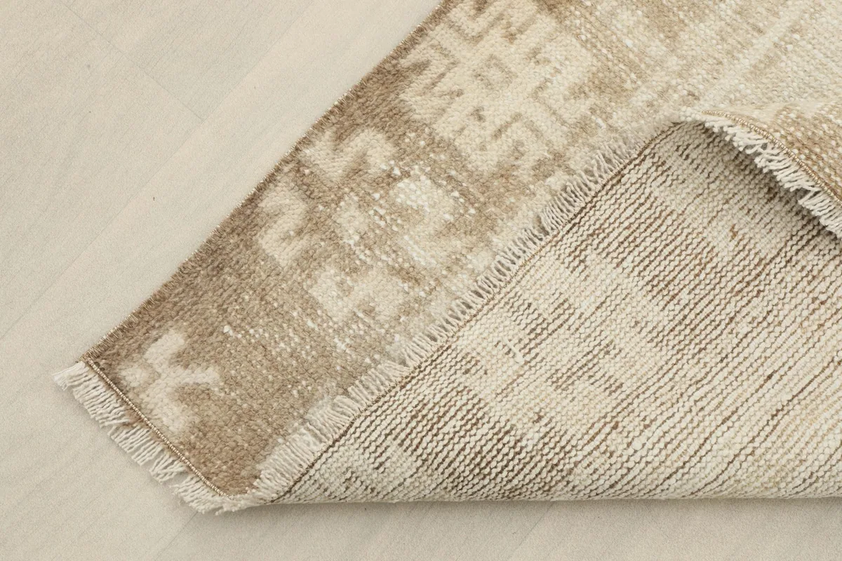 Corner of the rug folded to show the hand-knotted cotton foundation and wool pile