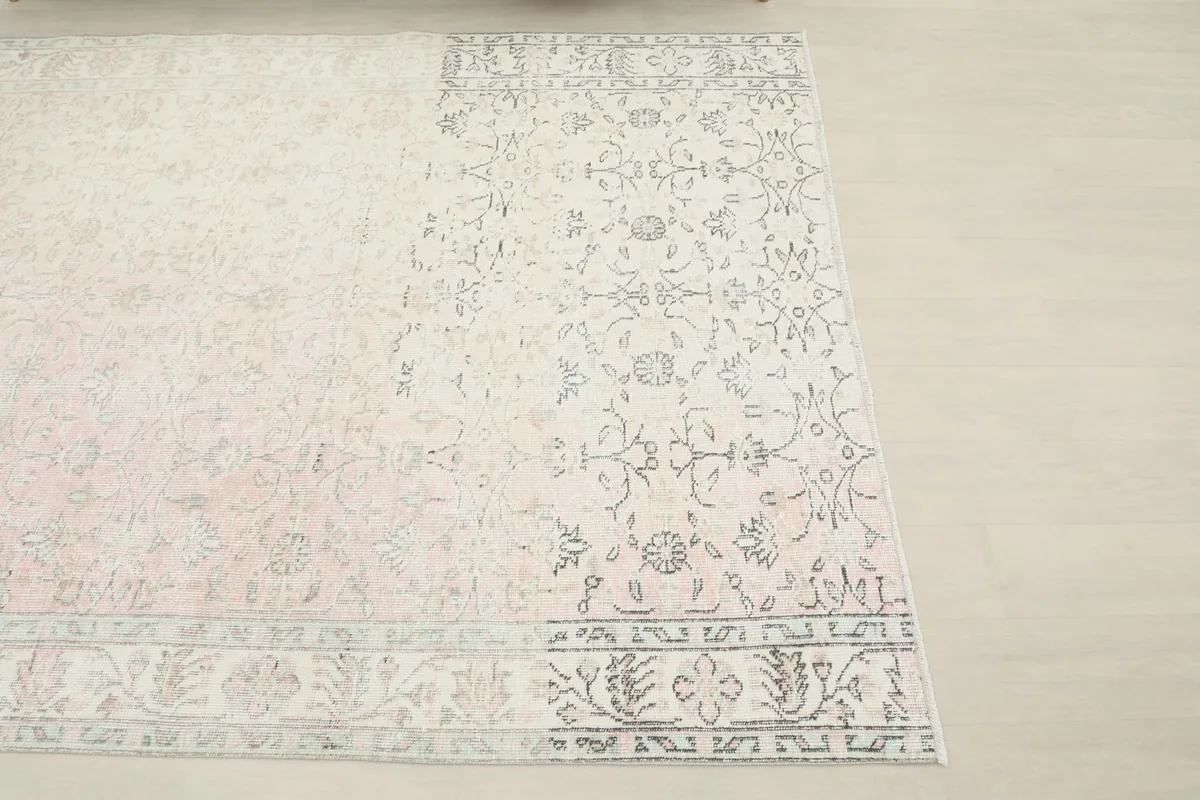 Overhead corner view highlighting the geometric border and softened floral design of the rug