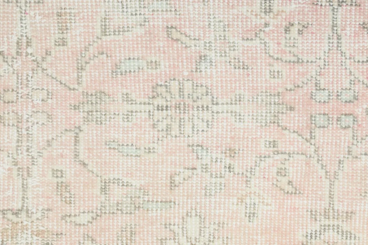 Detailed view of the rose-toned section of the rug, showing the wool pile and knotting