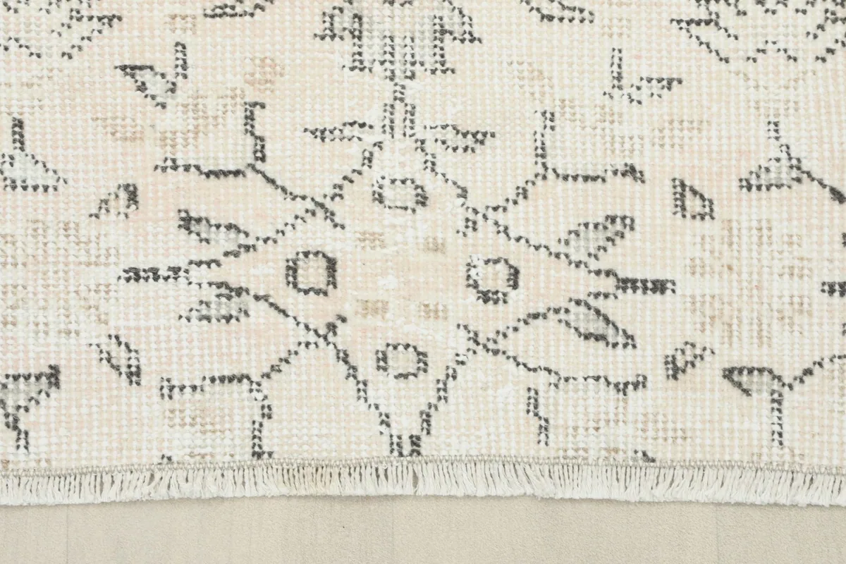 Close-up of the fringe and a section of the ivory field with geometric motifs