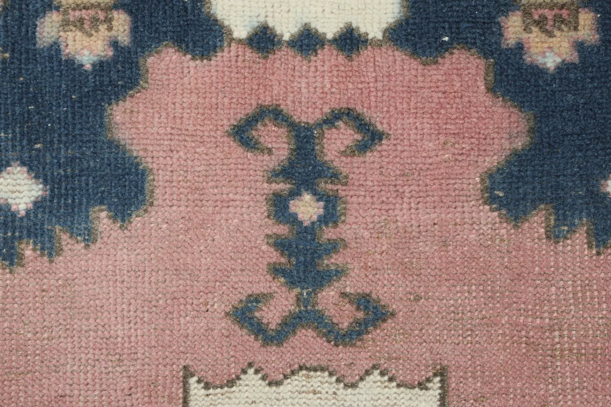 Close-up of a navy tribal motif on the rose field, showing the wool pile texture