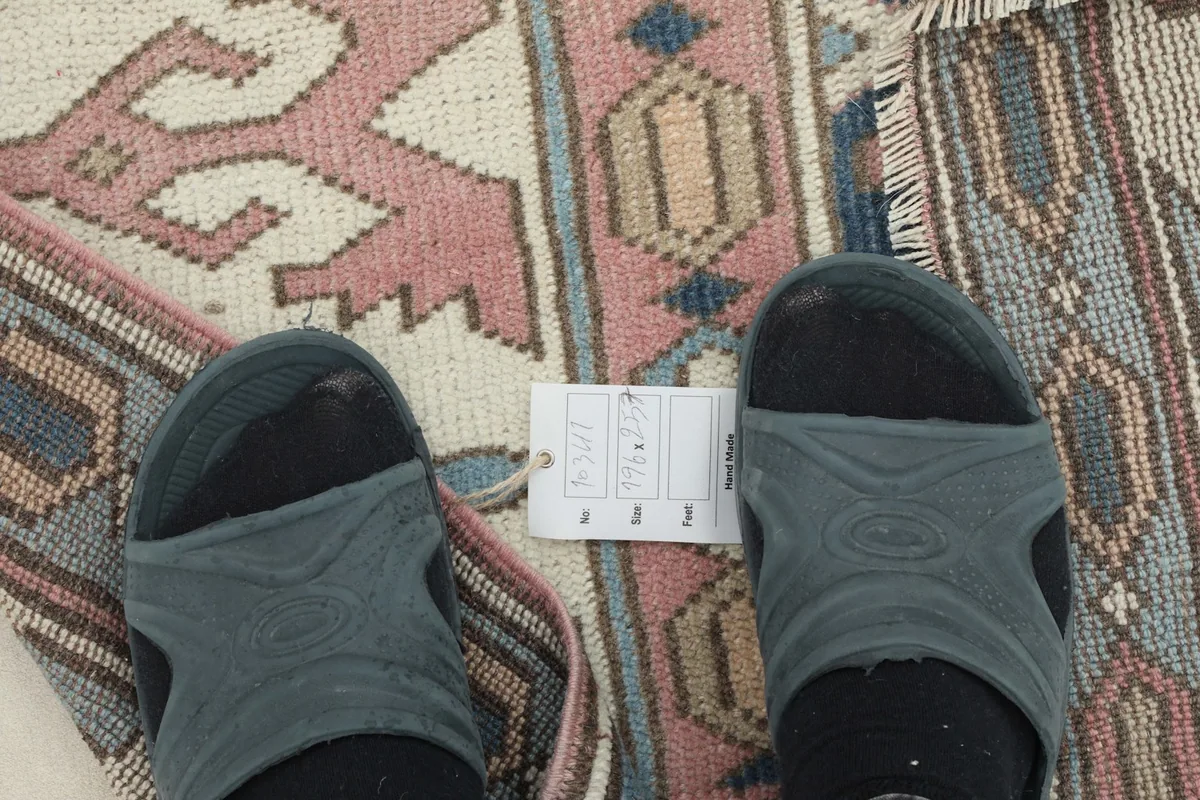 Overhead close-up of the rug's low pile and weave, with feet for scale
