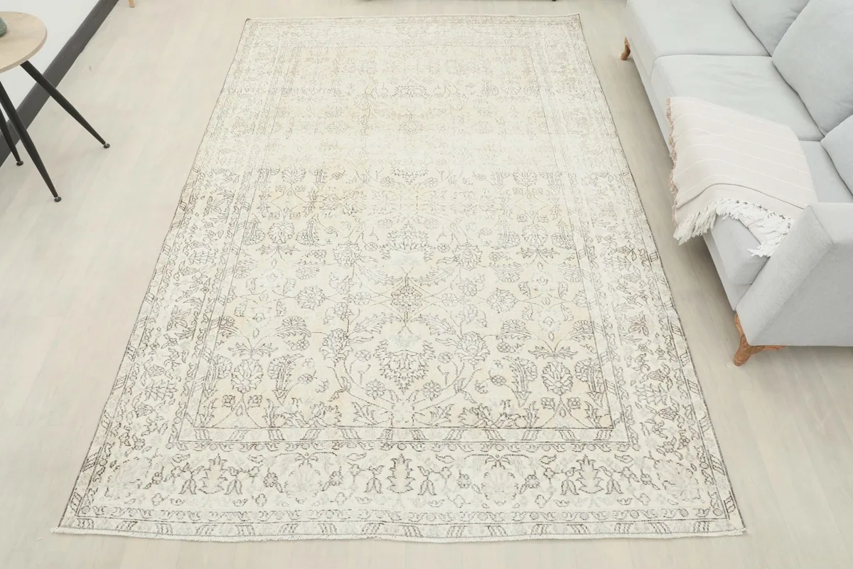 Wide shot of the ivory and gray vintage rug in a neutral-toned room with minimalist furniture