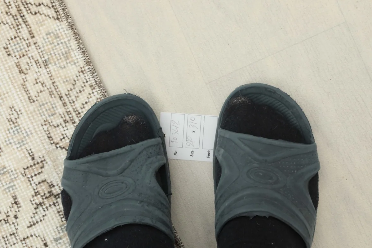 Feet next to a small card indicating the rug's dimensions for scale