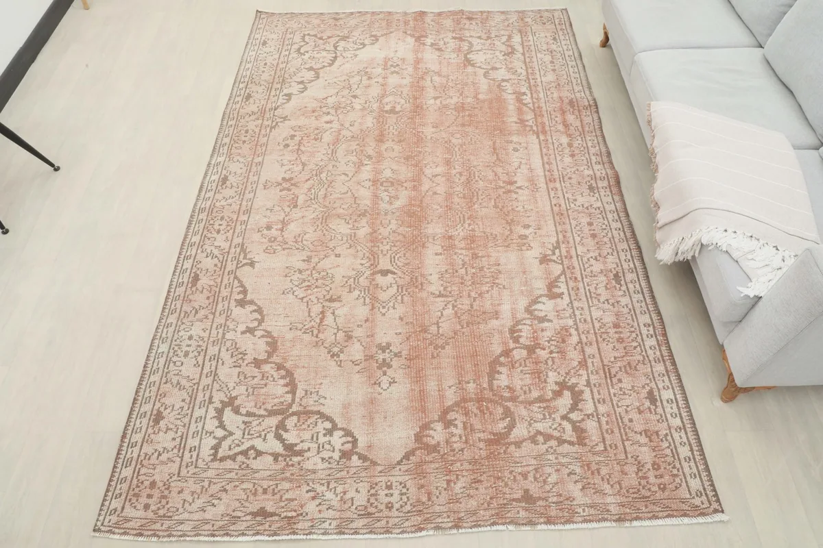 Overhead view of the vintage rose and beige rug laid out in a room, next to a sofa