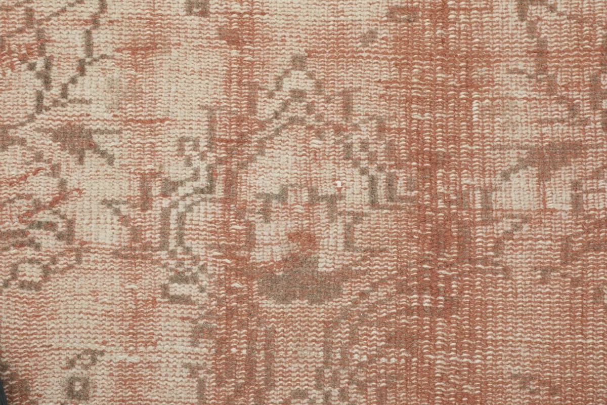 Detailed view of the rug's texture and faded rose and beige wool pile