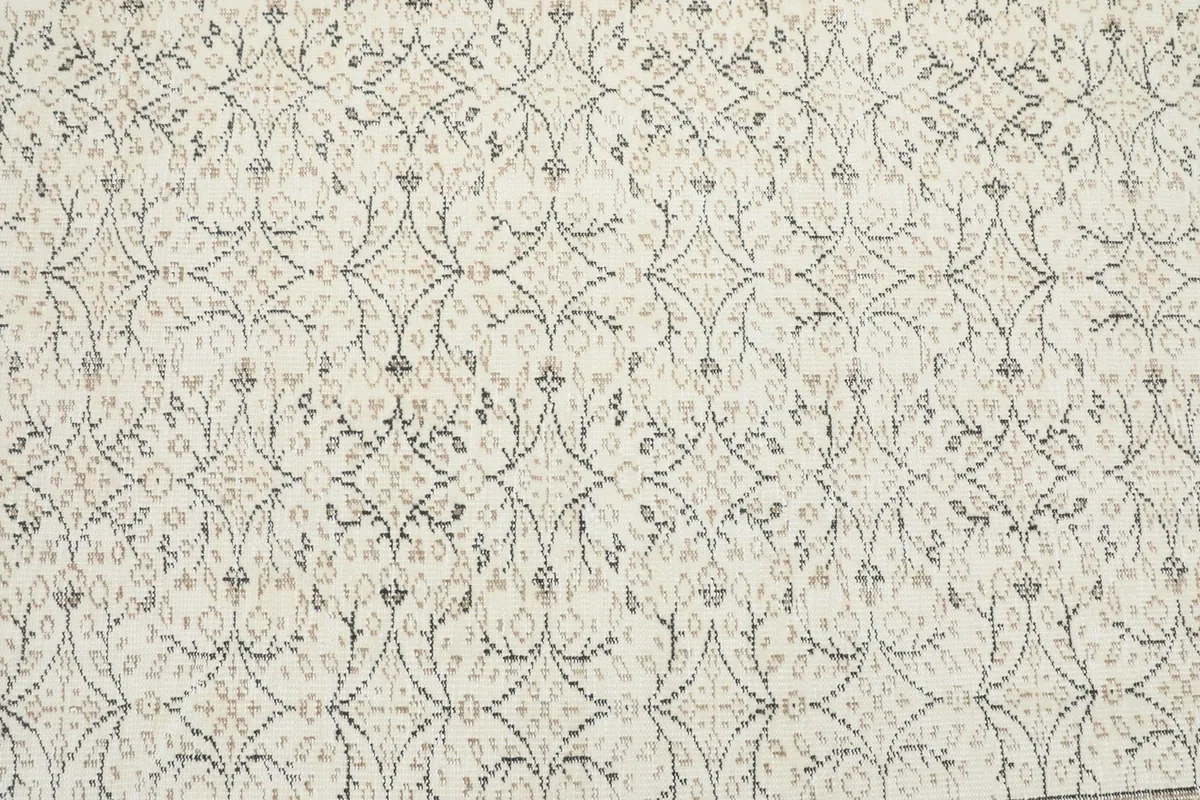 Detailed view of the rug's central field, showcasing the intricate ivory and brown geometric motifs