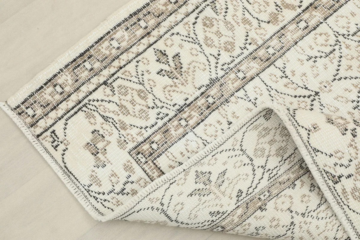 Corner of the rug folded back, showing the cotton foundation and the reverse side of the knots