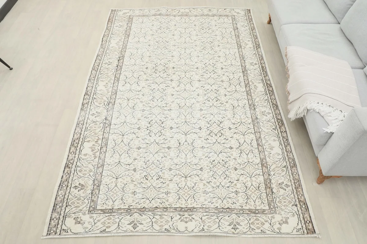 Full overhead view of the vintage ivory rug in a room setting, showing its placement relative to furniture