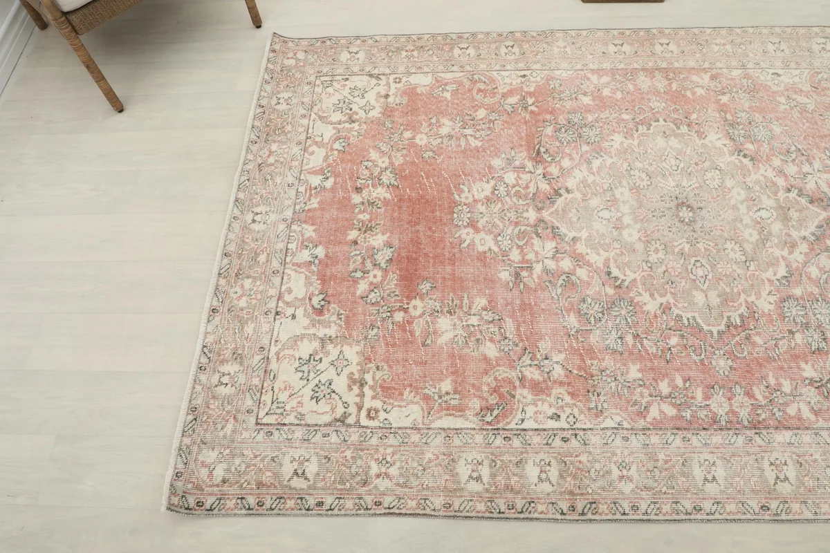 Corner view of the vintage Anatolian rug, highlighting the faded rose field and cream border