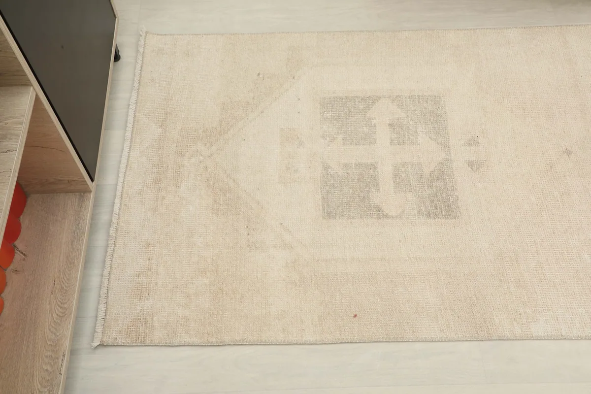 Overhead close-up of a faded geometric medallion motif on the rug's surface.
