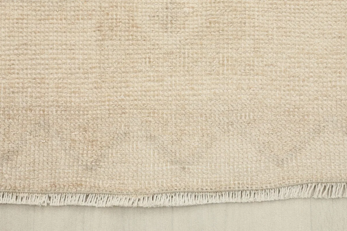 Close-up of the rug's short, natural wool fringe and the woven edge.