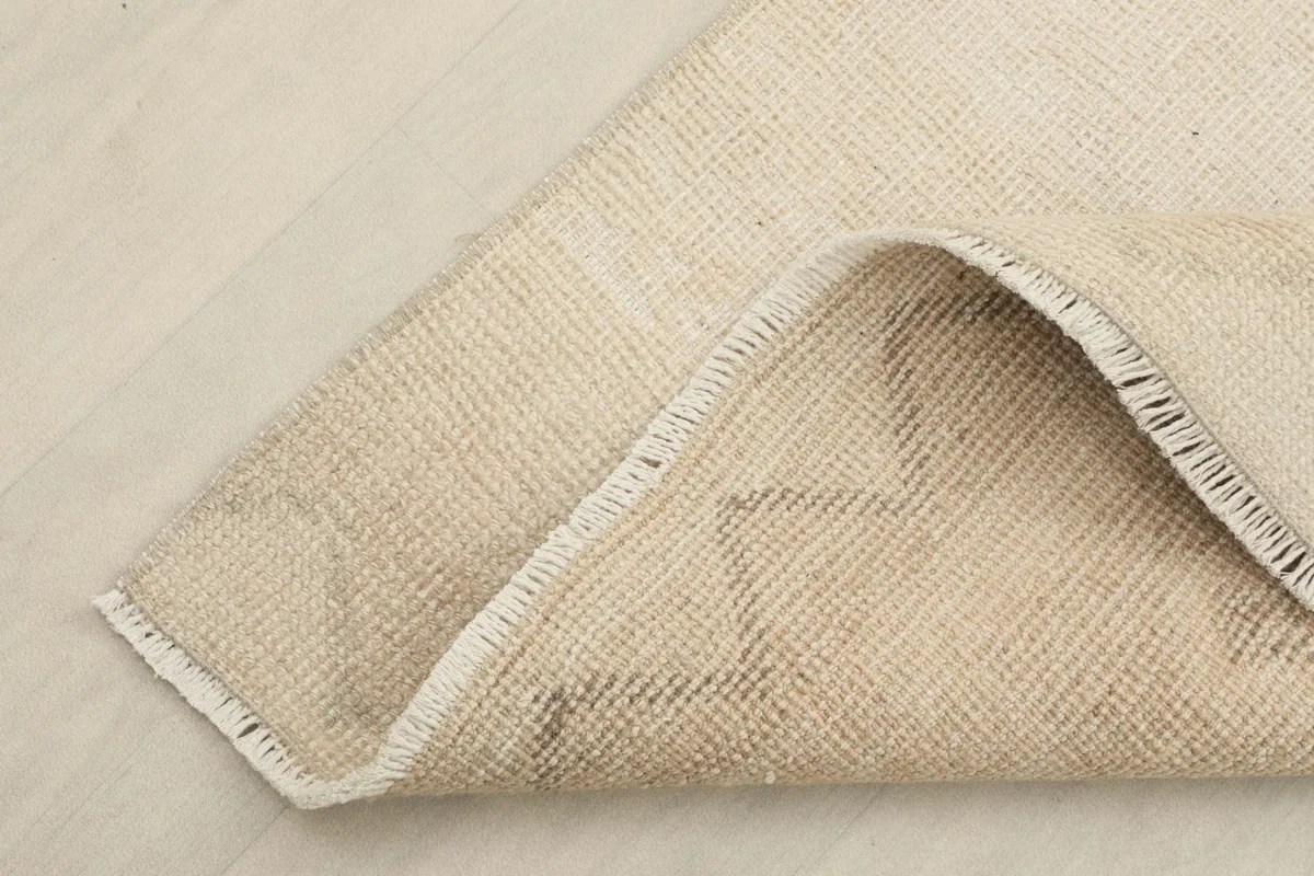 Corner of the rug folded back, showing the wool pile on a cotton foundation.